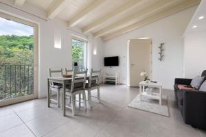 een woonkamer met een tafel, stoelen en een televisie bij Ca’ Scaì Agrifugium Elià in Tignale