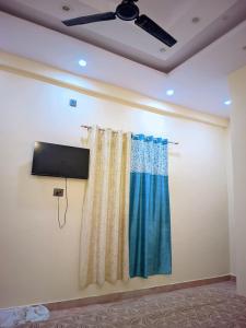 a room with a curtain and a tv on a wall at Hotel Pleasure Inn in Prayagraj