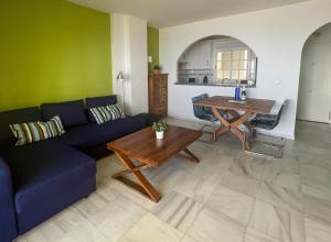 a living room with a blue couch and a table at First line Beach apartment in Torrox Costa