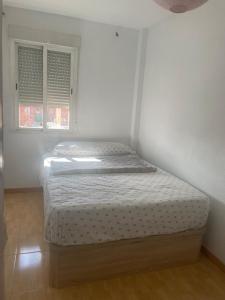 a bed in a white room with two windows at HABITACIÓN en chalet cerca Atocha in Madrid