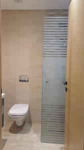 a bathroom with a toilet and a glass shower door at Appartement Cocooning de Sousse in Hammam Sousse +5 photos