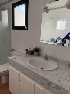 Un baño con lavabo, inodoro y espejo. en Villa Vera, en Playa Blanca
