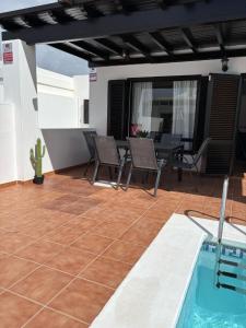 Un patio con mesa y sillas y una piscina. en Villa Vera, en Playa Blanca