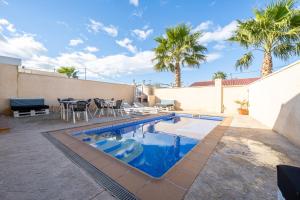 una piscina con mesa, sillas y palmeras en Casa Faro, en Camarles