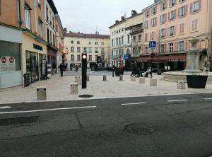 une rue urbaine avec un feu de signalisation et des bâtiments dans l'établissement Proche Gare, parking couvert, Wifi, à Bourgoin-Jallieu