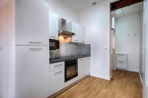 une cuisine avec des armoires blanches et un four à plaques de cuisson dans l'établissement Proche Gare, parking couvert, Wifi, à Bourgoin-Jallieu 3 autres photos