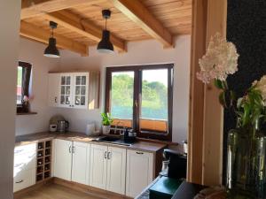 a kitchen with white cabinets and a window at Mahoniówka Mikołajki in Wawrowice