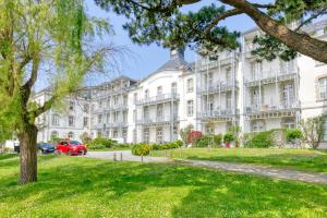 a large white building with a green lawn in front of it at Appartement face mer et Piscine in Le Croisic
