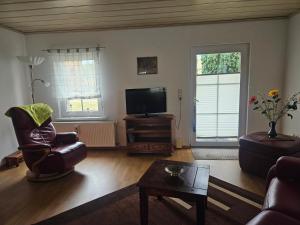 a living room with a tv and a chair and a table at Ferienhäuschen in der Nähe der Kirche in Rheinsberg