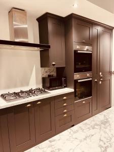 eine Küche mit braunen Schränken und einem Herd mit Backofen in der Unterkunft Stylish & Spacious Victorian Home near Severn Valley Railway & Safari Park in Kidderminster