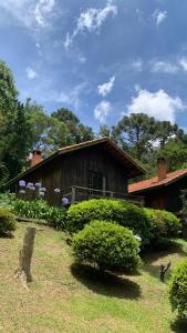 uma velha casa de madeira num quintal com arbustos em Pousada Bramasole em Monte Verde
