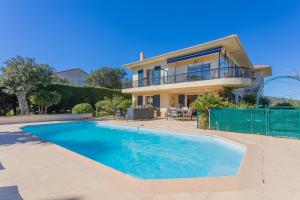 a house with a swimming pool in front of a house at Appartement Le Figuier in Fréjus