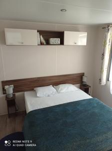 a bedroom with a bed with a wooden headboard at mobil home in Sainte-Reine-de-Bretagne