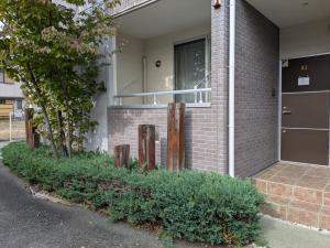a brick house with a porch and a window at Hana Hostel Fujisan Apartment in Fujiyoshida