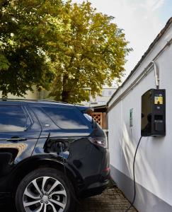 a car is plugged into a charging station next to a building at ante porta DAS STADTHOTEL in Trier