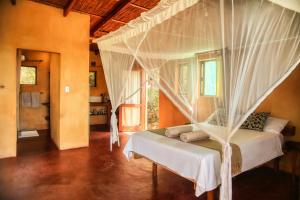 a bedroom with a bed with a mosquito net at Tree House Cottage, Ocean View in Praia do Tofo