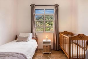 a bedroom with a crib and a window at Casa da Olides - T3 and Studio in Santana