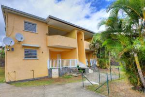 a yellow house with a palm tree in front of it at Le Poinsettia d'Or T3 élégant proche Maïdo & piscine in Le Bois de Nèfles