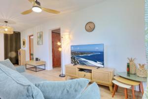 a living room with a blue couch and a clock on the wall at Le Poinsettia d'Or T3 élégant proche Maïdo & piscine in Le Bois de Nèfles