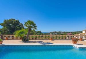 een zwembad voor een hek met een palmboom bij Casa Siempre Domingo in Moraira