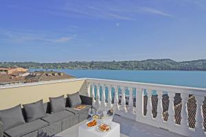 a balcony with a couch and a view of the water at Aa Imbarcadero apartments in Salò