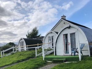 a small white house with a chair on a hill at Shannon Estuary Glamping Budget-Sustainable-Biodiversity-Rustic-Countryside Holiday Accommodation in Effernan