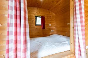Cama en una cabaña de madera con ventana en Tiny House, en Auriac-du-Périgord