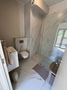 a bathroom with a toilet and a glass shower at Modern Simons Town Apartment near beach and penguins in Simonʼs Town