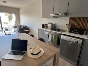 a kitchen with a table with a laptop on it at Modern Simons Town Apartment near beach and penguins in Simonʼs Town