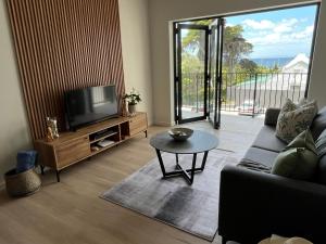 a living room with a couch and a tv and a table at Modern Simons Town Apartment near beach and penguins in Simonʼs Town +64 photos