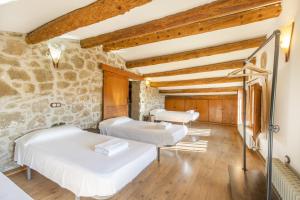 - 2 lits dans une chambre avec un mur en pierre dans l'établissement Mas Vilardaga, à La Baronia de Rialb
