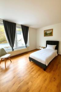 a bedroom with a bed and a chair and two windows at Großes Ferienhaus in Siegen-Kreuztal auch für Monteure in Kreuztal