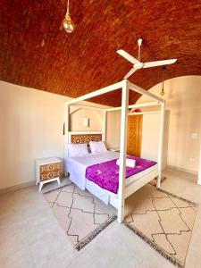 a bedroom with a white bed with purple sheets at Royal Home Dome Style - Top Floor Apartment in Jazīrat al ‘Awwāmīyah +2 photos