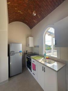 a white kitchen with a refrigerator and a sink at Royal Home Dome Style - Top Floor Apartment in Jazīrat al ‘Awwāmīyah