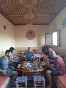 Eine Gruppe von Männern, die um einen Tisch sitzen. in der Unterkunft Dar Bani in Zagora + 75 Fotos
