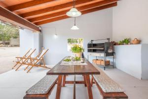 a dining room with a wooden table and benches at Son Bessó in Font de Sa Cala