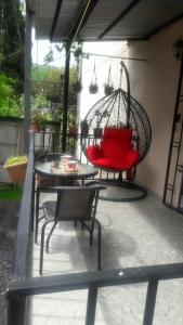 a swing on a patio with a table and chairs at Dachi in Itʼkhvisi