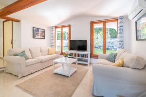 a living room with two couches and a tv at Can Botana 10 in Cala de Sant Vicent