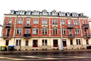 a large red brick building on the side of a street at Helles Geräumiges Appartement - 10 Min zur Neustadt - Kostenloses Parken - Dresden365 in Dresden