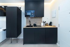 a kitchen with black cabinets and a sink and a microwave at LUXURY APARTMENT JACUZZi in Málaga