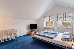 バート・ベルレブルクにあるHaus Waldblickのベッドルーム1室(ベビーベッド1台、テレビ、窓2つ付)