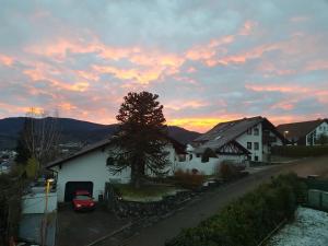 ein Sonnenuntergang über einem Haus mit einem Baum und einem Auto in der Unterkunft Schusters Murgtalblick in Gernsbach