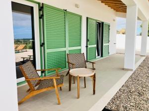 two chairs and a table on a porch with green shutters at Casa Elo - Fresh-Built Home with Pool in Alcorochel