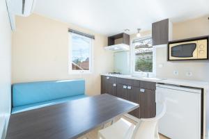 eine Küche mit einem Holztisch und einem blauen Sofa in der Unterkunft Falaguera Bungalow 2 in Simat de Valldigna