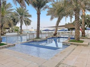 una piscina con palmeras en un resort en VayK - Beachfront 1BR with Sea Views in Palm Jumeirah, en Dubái