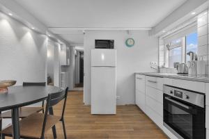 a white kitchen with a table and a refrigerator at Castle Inn Apartments - Downtown Keflavík in Keflavík