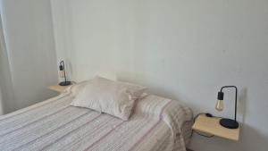 a white bedroom with a bed with two lights on it at Delvi Nelly - Belgrano in Neuquén