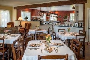 a restaurant with white tables and chairs and a kitchen at Ravenscroft Inn in Port Townsend
