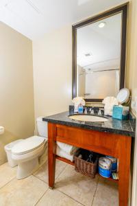 a bathroom with a sink and a toilet and a mirror at Honua Kai 1024 · HK 1024 Updated Beachfront Luxury Condo w Pool in Lahaina +56 photos