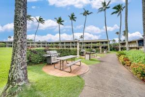 a park with benches and palm trees in front of a building at Napili Shores E240 · NS E240 Beautiful Condo w AC Close to Napil in Kahana